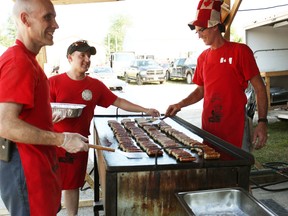 On the right, Huron East firefighter Steve Eckert mans the sausage grill on Canada Day at the Huron East Fire Station in Seaforth for the popular Seaforth Fire Fighter’s Breakfast. (Shaun Gregory/Huron Expositor)