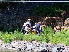 Northwest EMS transport a patient to a waiting ambulance while emergency responders continue to search for possible drowning victims in the vicinity of the railway bridge at McLeod Park, Thursday, July 5.
Reg Clayton/Daily Miner and News