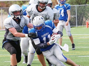Carter Struk, right, of the Sudbury Gladiators senior varsity team, attempts to evade Oakville Titans defenders during football action at the James Jerome Sports Complex in Sudbury, Ont. on Saturday May 28, 2016. John Lappa/The Sudbury Star/Postmedia Network