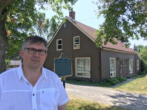 Gus Panageotopoulos stands in front of a house in Bath that dates from the beginning of the village, and a structure he says should get heritage protection. (Elliot Ferguson/The Whig-Standard