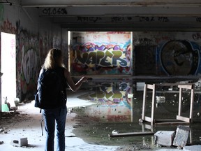 Street Outreach Coordinator Amanda Brierley inspects the old Kingston Park Raceway bleachers with her flashlight on June 29, 2018. The site was vacant at the time of the Friday's outreach, but signs of recent inhabitants were apparent. (Iain Sherriff-Scott/The Whig-Standard/Postmedia Network)