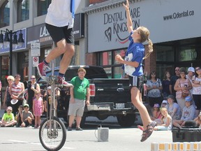 Groovy Guy holds a $5 bill high in the air as 11-year-old Hannah Noble-Duphney jumps up to try and grab it at his show on Princess St. for the second day of the Kingston Busker Rendezvous. Brigid Goulem for the Whig-Standard/Postmedia Network