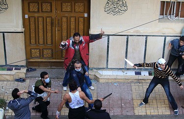An Egyptian Muslim (in red) and some Christians attempt to stop other Christians, including some holding knives, from entering a mosque beside the the Coptic Orthodox church in Alexandria, 230 km (140 miles) north of Cairo on Jan. 1, 2011. (REUTERS)