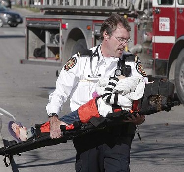 A medical supervisor carries a child who was injured in a multi-vehicle collision in Winnipeg September 29. Brian Donogh/QMI Agency