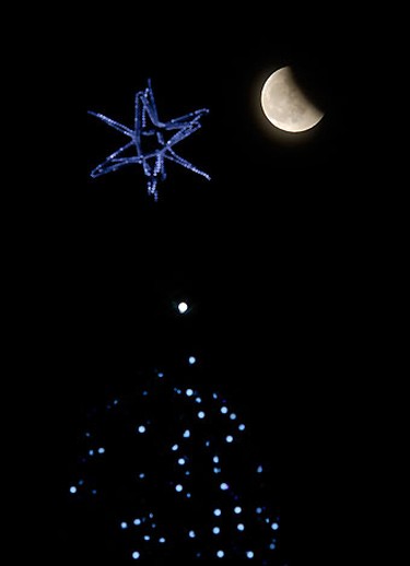 The shadow of the Earth falls across the face of the Moon, with a six-pointed decorative star on a Christmas tree in the foreground, above Russia's far eastern city of Vladivostok during a full lunar eclipse December 21, 2010. The eclipse is the first to coincide with the Winter Solstice since 1638.  REUTERS/Yuri Maltsev