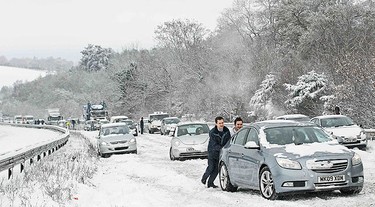 Motorists push a car in the snow on the A3 near Guildford, in southern England on Dec. 18, 2010. Fresh snow brought much of Britain to a standstill on Saturday, on what is traditionally the busiest weekend for shopping and travel in the run-up to Christmas.    (REUTERS)