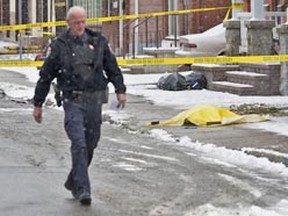 A yellow tarp covers evidence in front of homes and businesses along Booth St. Monday morning after a teen was shot dead inside a vehicle and dumped onto the sidewalk. (ERROL McGIHON Ottawa Sun)