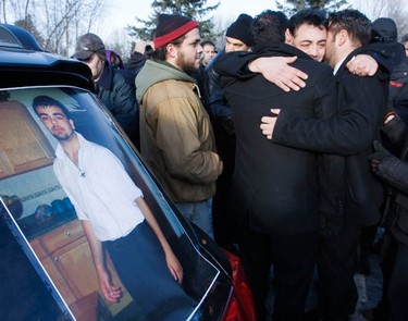 Ali Ghiasi, right, the father of murder victim, Yazdan Ghiasi, pictured left, is embraced by family and friends during the burial service at Beechwood Cemetery Thursday, December 9, 2010.  (Darren Brown/Ottawa Sun)