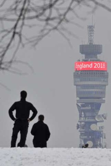 A couple stand in the snow on Primrose Hill as they look towards a 2018 soccer world cup finals slogan on the BT communication tower in central London Friday. (REUTERS/Toby Melville)