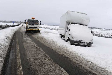 A snow plough goes past a vehicle stranded due to snow on the A57 road near Worksop, northern England Friday. Around 200 people were stranded on the road overnight and had to be rescued by mountain rescue crews after heavy snowfall, local media reported. (REUTERS/Nigel Roddis)