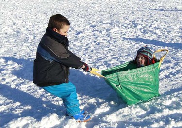Jude Veitch sits in a plastic bag as his brother Morgan pulls him across the snow at the Queen Elizabeth country park near Petersfield in southern England on Friday. (REUTERS/Luke MacGregor)