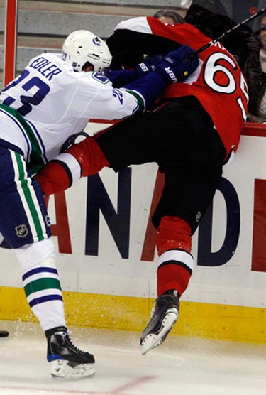 Ottawa Senators' Erik Karlsson (65) is checked into the boards by Vancouver Canucks' Alexander Edler (23) during the second period of NHL action at Scotiabank Place Thursday, November 11, 2010. (Darren Brown/Ottawa Sun)