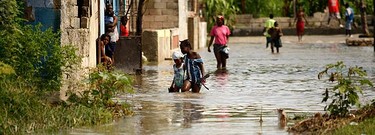 Haitians walk in a street after a drain flooded their neighborhood of Cite-Soleil in Port-au-Prince on Nov. 6, 2010. Hurricane Tomas soaked Haiti's crowded earthquake survivors' camps and swamped coastal towns on Friday, triggering flooding and mudslides that killed at least seven people. (REUTERS)