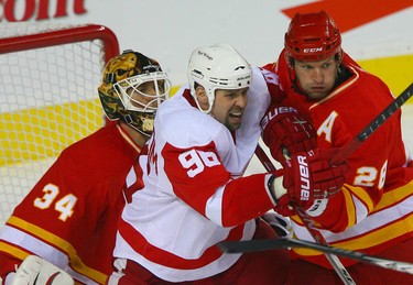 Flames goalie Miikka Kiprusoff (L) tries to see past Tomas Holmstrom  (C) and Flames' defenceman Robyn Regehr (R) during NHL action between the Detroit Red Wings and the Calgary Flames in Calgary November 3, 2010 at the Scotiabank Saddledome.
JIM WELLS / CALGARY SUN/ QMI AGENCY