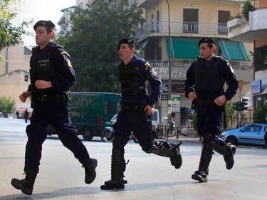 Greek policemen run for cover seconds before a controlled explosion of a suspicious package at a courier company (seen in the background at the right) some 300 metres from the Presidential residence in Athens Nov. 2, 2010.  Greek police detonated a parcel bomb addressed to the German embassy at the courier company in Athens, shortly after a bomb went off at the Swiss embassy and another was found at the Bulgarian embassy.   (REUTERS)