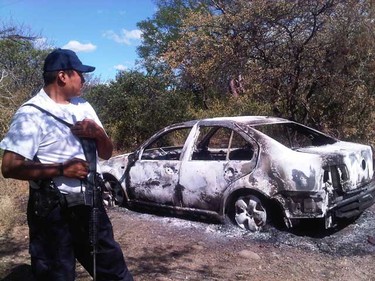 A Mexican police officer stands by the burned Volkwagen Jetta containing the body of Carleton place-area man Daniel Dion. Dion's body was found late Saturday in the mountainous region on the outskirts of Guerrero in Mexico. He had been missing since Oct. 22. (Photos courtesy Dion family)