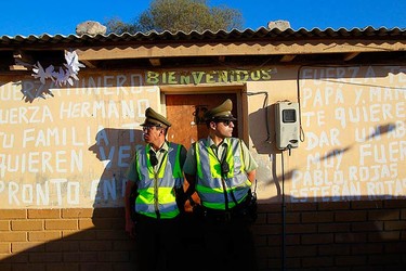Policemen stand guard in front of the home of rescued Chilean miner Victor Segovia after his arrival. The banner reads, "be strong miners, be strong brother, your family loves you, back soon (L), be strong, your mother and father want to give you a strong hug". (REUTERS)