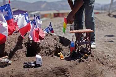 A neighbour of Chilean miner Claudio Acuna plants a Bolivian flag next to Chilean ones while building a scale model of a mine with the winch and capsule that were used in the rescue of Acuna and 32 other miners trapped for 69 days in the San Jose mine, as they prepared a reception party for him in Copiapo on Oct. 15, 2010. (REUTERS)