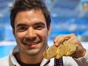 Canada's Alexandre Despatie poses with his three gold medals won during diving events at the Commonwealth Games in New Delhi October 12, 2010. (REUTERS/Andy Clark)