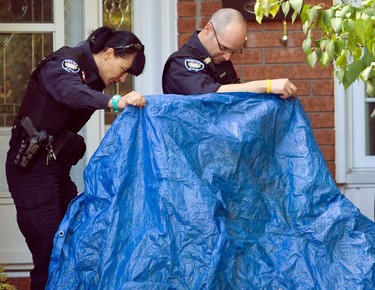 Two police officers take a look at the dead moose before it was removed. Ottawa Police tracked a moose from North Service Rd and Trim Rd in Orleans to a subdivision at Wilkie Dr. and Chenier Way in Orleans Monday, October 11, 2010. The moose stopped in the front walkway of a home before collapsing and reportedly dying of exhaustion. The homeowners were out of town and returned to see the moose removed.