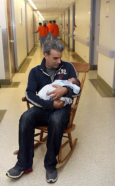 Sergio Vettese holds his newborn baby before a move to Sunnybrook. A team of movers gathered equipment in the hallway as he waited on Sept. 12, 2010. (VERONICA HENRI, Toronto Sun)