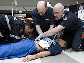 Paramedics showing the steps taken when providing care to a cardiac arrest victim in a first aid/CPR course. (Greg Henkenhaf/QMI Agency)