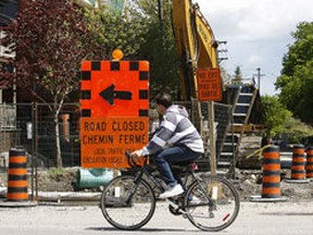 A cyclist rides past road construction.
TONY CALDWELL/Ottawa Sun