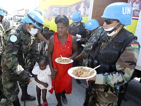 Bolivian UN troops keep guard as child, women and men line up for plates of food in Port au Prince, Haiti Jan 15, 2010. (Andre Forget/QMI AGENCY)