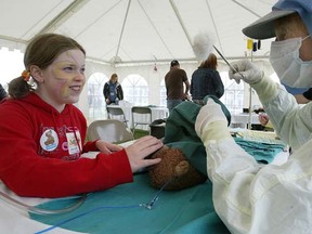 Aimee Hanson (left) watches as her bear "Bearry" is treated by nursing student Twyla Popoff at the annual Teddy Bears' Picnic on May 31, 2009. This year's Teddy Bear Picnic goes Sunday. (Brian Donogh/SUN MEDIA)