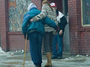 A Good Samaritan helps another lady on crutches cross the icy sidewalk outside the Salvation Army Booth Center on Main Street, as Winnipeg experiences another treacherous, icy day. (Marc Evans/FOR SUN MEDIA)