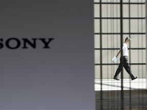A man is seen behind a logo of Sony Corp at its headquarters in Tokyo in this July 30, 2009 file photo. Reuters/Kim Kyung-Hoon/Files