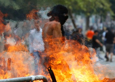 A masked youth walks beside a burning barricade during clashes in Athens' central Syntagma (Constitution) Square June 15, 2011. REUTERS/Yannis Behrakis
