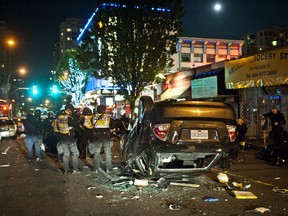 Members of the Vancouver police riot squad stand by an over-turned police car during last week's hockey riot. (CARMINE MARINELLI/QMI AGENCY)