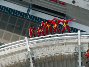 The Toronto Sun's Jenny Yuen (second from the left) hangs out over Toronto at the CN Tower's new EdgeWalk attraction. (MICHAEL PEAKE/Toronto Sun)