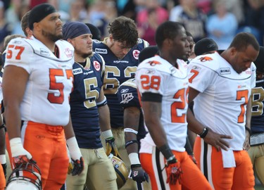 Winnipeg Blue Bombers Scott McHenry (#5) and Steve Morley (#62) along with BC Lions (l-r) Andrew Jones, J.R. Ruffin and Jarious Jackson react during a moment of silence for Bombers assistant coach Richard Harris in Winnipeg July 28, 2011.
BRIAN DONOGH/WINNIPEG SUN/QMI AGENCY