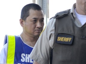 Vince Weiguang Li, left, is escorted by sheriff officers on his way to a court appearance in Portage la Prairie in this August 5, 2008 file photo. (REUTERS/Fred Greenslade/Files)