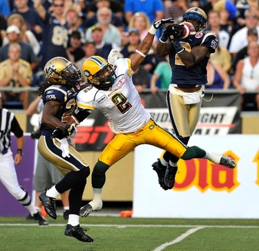 Winnipeg Blue Bombers' Jovon Johnson (R) intercepts the ball in front of Edmonton Eskimos' Fred Stamps (2) during the second half of their CFL game in Winnipeg, August 5, 2011. REUTERS/Fred Greenslade (CANADA - Tags: SPORT FOOTBALL IMAGES OF THE DAY)