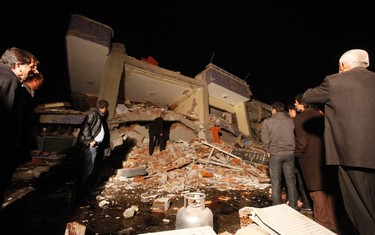 Survivors stand in front of a collapsed building in Ercis, near the eastern Turkish city of Van, October 23, 2011. As many as 1,000 people were feared killed on Sunday when a powerful earthquake struck Turkey, collapsing dozens of buildings and pulling down phone and power lines in the southeast of the country, officials and witnesses said. REUTERS/Osman Orsal