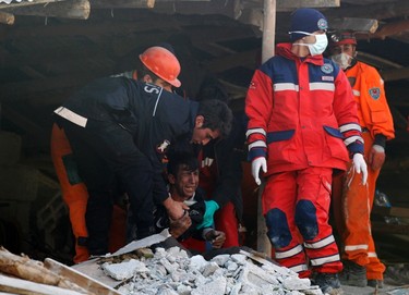 Rescue workers comfort a man who lost his relative after an earthquake in Ercis, near the eastern Turkish city of Van, early October 24, 2011. (REUTERS/Umit Bektas)