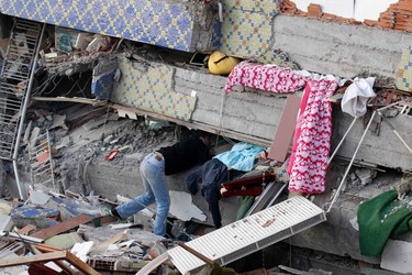 A man searches for his relatives under a collapsed building after an earthquake in Ercis, near the eastern Turkish city of Van, early October 24, 2011. (REUTERS/Umit Bektas)