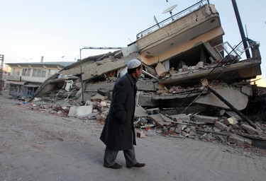 A survivor walks in front of a collapsed building in Ercis, near the eastern Turkish city of Van, October 24, 2011. More than 200 people were killed and hundreds more feared dead on Monday after an earthquake struck parts of southeast Turkey, where rescue teams worked through the night to try to free survivors crying for help from under rubble. (REUTERS/Osman Orsal)