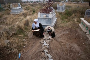 A woman prays as the other mourns while sitting next to a grave of their relative, killed during an earthquake, in Ercis October 25, 2011. (REUTERS/Morteza Nikoubazl)