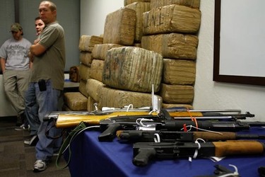 Guns and bundles of marijuana seized from the Mexican Sinaloa Cartel during "Operation Pipeline Express" are displayed at a news conference in Phoenix, Arizona October 31, 2011. Law enforcement authorities have arrested over 70 people in raids that dismantled a narcotics trafficking network suspected of smuggling nearly $2 billion worth of drugs through Arizona's western desert, officials said on Monday.  (REUTERS/Joshua Lott)