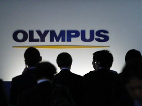 People walk past a sign of Olympus Corp outside the company's showroom in Tokyo Nov. 10, 2011.   REUTERS/Toru Hanai