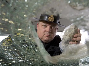 A file photo shows a police officer peering through a smashed car windshield. (QMI Agency files)