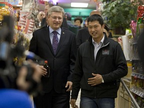 In this February 2011 file photo, Prime Minister Stephen Harper is seen with shopkeeper David Chen, who was charged with assault and forcible confinement after chasing, restraining and tying up a man who had stolen plants from his store in May 2009.  (Jack Boland/QMI AGENCY)