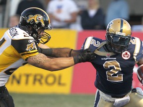 Winnipeg Blue Bombers Jovon Johnson breaks a tackle by Hamilton Tiger-Cats Daryl Stephenson during CFL action in Winnipeg Friday August 26, 2011. (BRIAN DONOGH/QMI Agency)