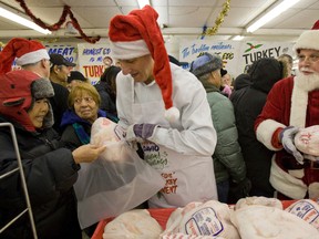 David Mirvish and Santa hand out the turkey and fruit cake in 2011 as part of Honest Ed's annual turkey giveaway. (DAVE THOMAS/Toronto Sun)