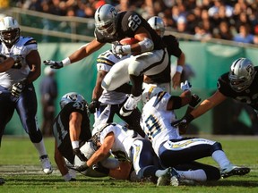 Raiders running back Michael Bush leaps over Chargers defenders while rushing with the ball in Oakland, Calif., Jan. 1, 2012. (ROBERT GALBRAITH/Reuters)