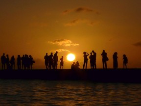 Tourists watch the sun setting over a point on Waikiki Beach in Honolulu December 26, 2011.  REUTERS/Jason Reed